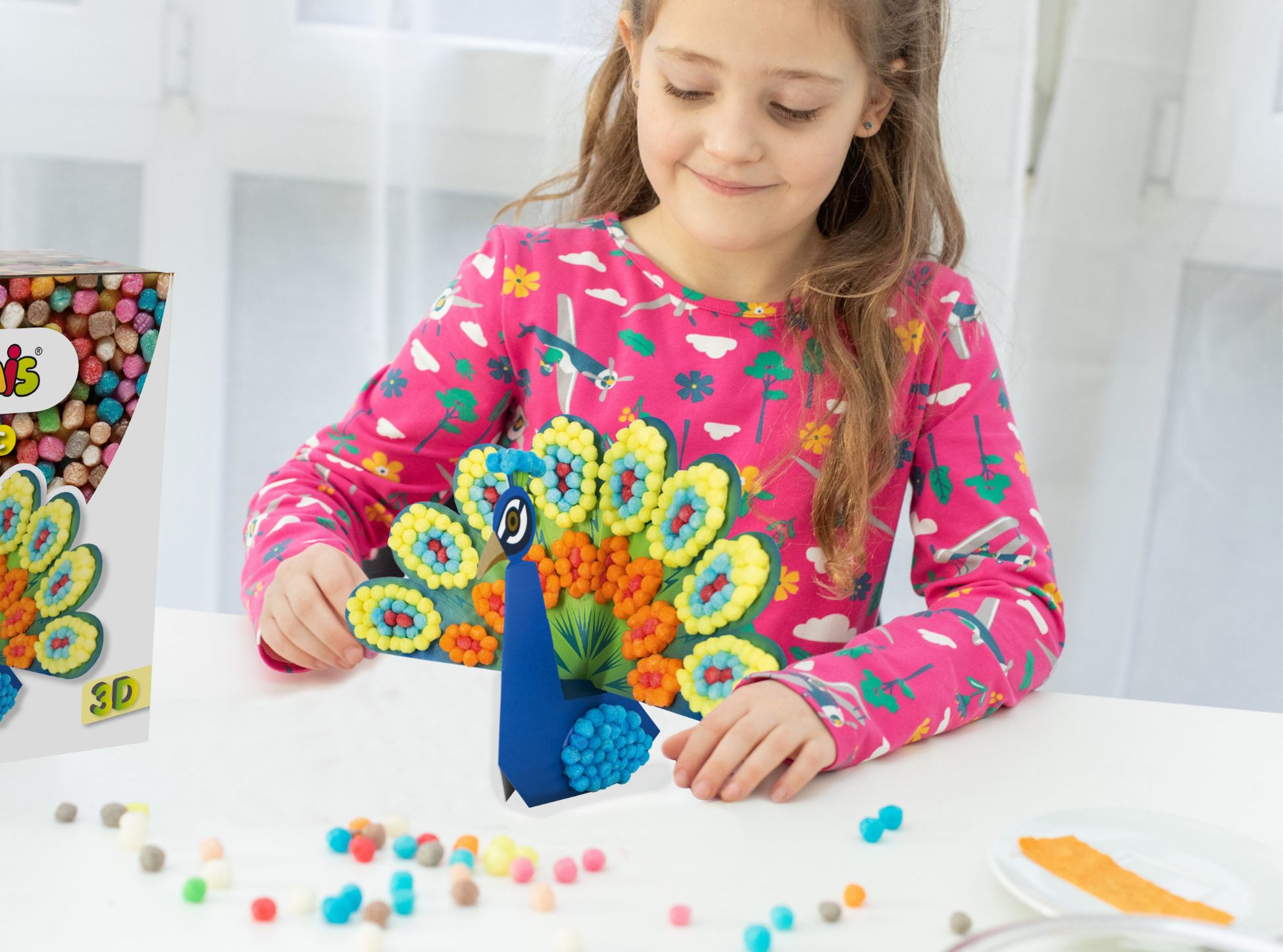 Une jeune fille construit un paon avec des billes Playmais